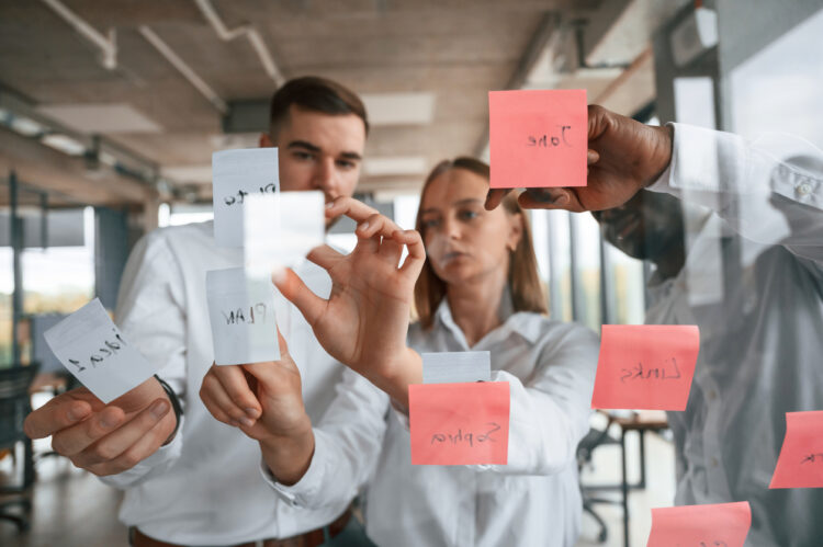 Stickers on the glass, planning the project. Group of office workers are together indoors