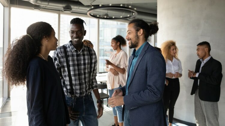 Smiling black male manager talk to clients at office space